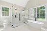 Bathroom with a stall shower, a freestanding tub, lofted ceiling, and tile patterned floors
