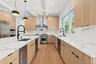 Kitchen with light stone counters, modern cabinets, light wood-style floors, decorative light fixtures, and light brown cabinetry