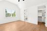 Unfurnished bedroom with vaulted ceiling, light wood finished floors, a spacious closet, a ceiling fan, and ensuite bathroom