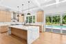 Kitchen featuring modern cabinets, light stone countertops, light wood-style floors, hanging light fixtures, and beamed ceiling