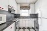 Kitchen featuring white appliances, dark countertops, light flooring, and under cabinet range hood