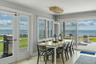Dining space seamlessly connected to kitchen and living room with panoramic water views.