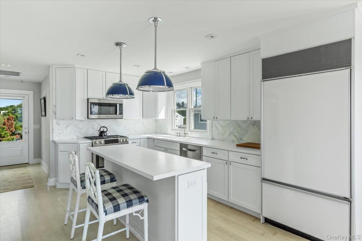 Updated custom kitchen with stainless steel appliances, sleek white cabinetry and quartz countertops.