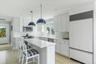 Updated custom kitchen with stainless steel appliances, sleek white cabinetry and quartz countertops.