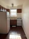 Kitchen featuring dark wood-style flooring, light countertops, white appliances, baseboards, and a sink