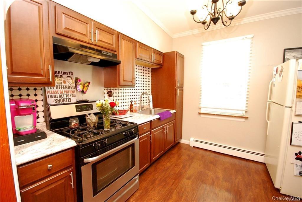Rear building second floor Kitchen with stainless steel gas range oven, backsplash, freestanding refrigerator, under cabinet range hood, and crown mol