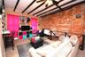 Carpeted living area featuring beamed ceiling, brick wall, a ceiling fan, and a baseboard radiator