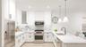 Kitchen with a peninsula, a sink, white cabinets, appliances with stainless steel finishes, and decorative light fixtures