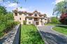 Mediterranean / spanish-style home with stairway, stucco siding, asphalt driveway, a chimney, and a front lawn