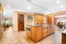 Kitchen featuring stainless steel microwave, recessed lighting, light stone counters, an island with sink, and a chandelier