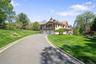 Mediterranean / spanish-style home with stucco siding, an attached garage, a chimney, driveway, and a tile roof
