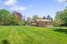 View of green lawn featuring driveway and an attached garage