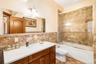 Bathroom featuring a chandelier, vanity, enclosed tub / shower combo, and tile walls