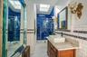 Main Floor Full bathroom with a skylight, a walk in  shower, custom tile patterned flooring, and tile walls