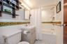 Full Bathroom with toilet, vanity, tile walls, wainscoting, and shower/tub combo