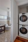 Laundry room featuring stacked washer and clothes dryer, electric panel, hardwood / wood-style floors, and tile walls