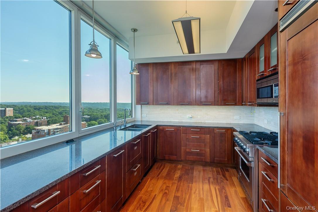 Kitchen featuring hardwood / wood-style flooring, decorative light fixtures, backsplash, and built in appliances