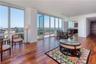 Living room with dark hardwood / wood-style flooring, track lighting, and a wall of windows