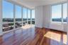 Empty room with plenty of natural light, a wall of windows, dark hardwood / wood-style flooring, and radiator heating unit