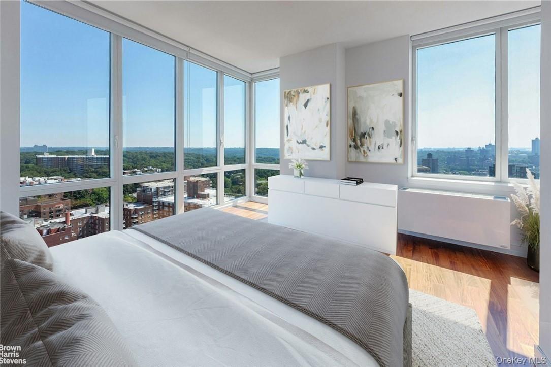 Bedroom with radiator heating unit, expansive windows, and wood-type flooring