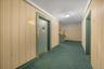 Corridor featuring stairway, elevator, wallpapered walls, and dark carpet