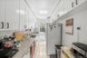 Kitchen featuring white appliances, white cabinets, light tile patterned floors, backsplash, and light stone countertops