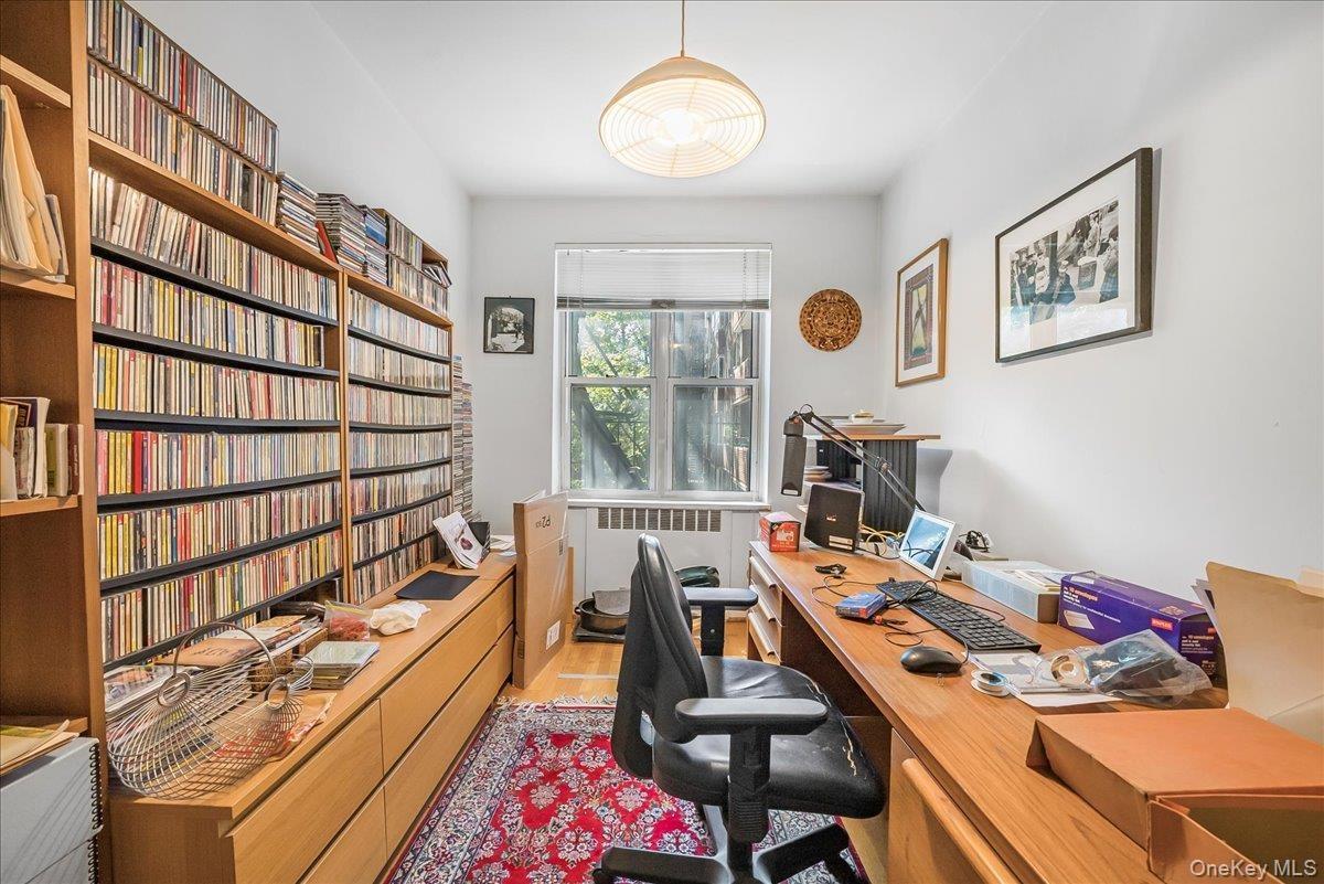 Home office with radiator heating unit and light wood finished floors