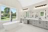 Full bathroom featuring a stall shower, double vanity, a freestanding bath, lofted ceiling, and light tile patterned flooring