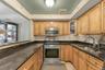 Kitchen featuring light tile patterned flooring, stainless steel appliances, sink, and dark stone counters