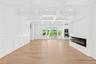 Unfurnished living room with a decorative wall, beamed ceiling, a glass covered fireplace, recessed lighting, and light wood-style flooring