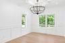 Unfurnished dining area featuring a decorative wall, wainscoting, light wood-type flooring, a chandelier, and ornamental molding