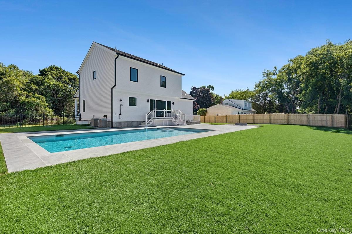 Rear view of house with a fenced backyard, a patio, and view of scattered trees