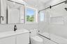 Bathroom featuring vanity, tile walls, combined bath / shower with glass door, and recessed lighting