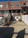 Rear view of property with brick siding, fence, stairs, cooling unit, and driveway
