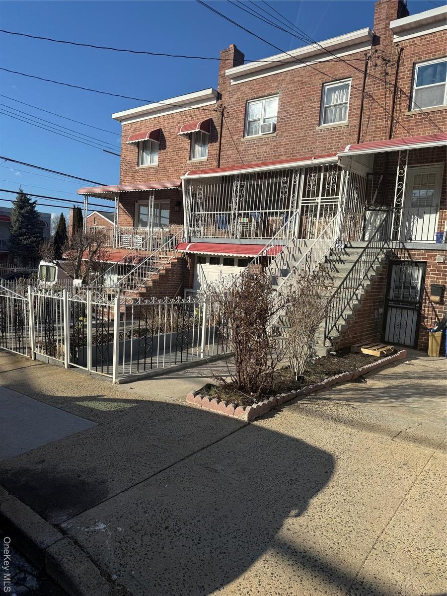 View of property featuring stairway, fence, brick siding, and a chimney