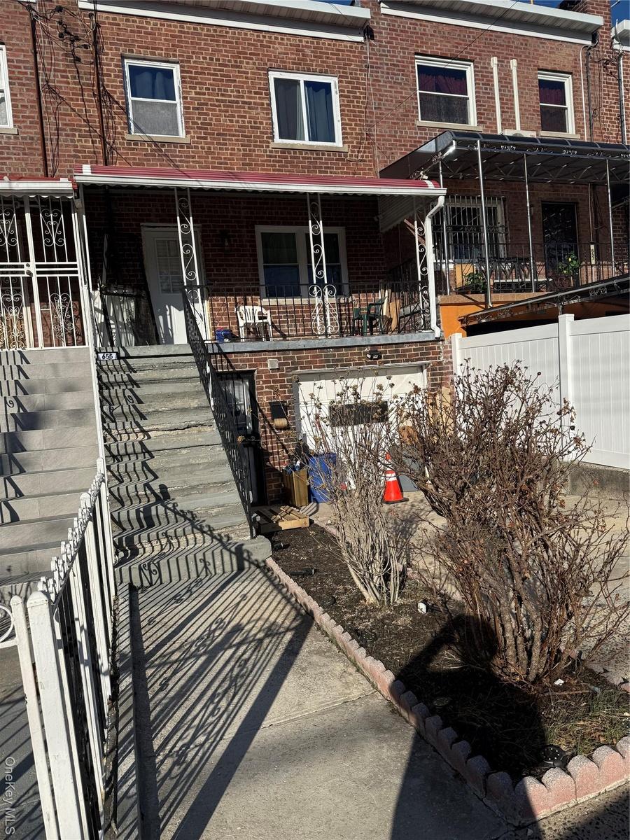 Townhome / multi-family property with brick siding, covered porch, and stairs