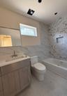 Full bathroom with tile walls, vanity, washtub / shower combination, and light marble finish flooring
