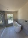 Bathroom with tile walls, wainscoting, a shower stall, a freestanding tub, and marble finish flooring