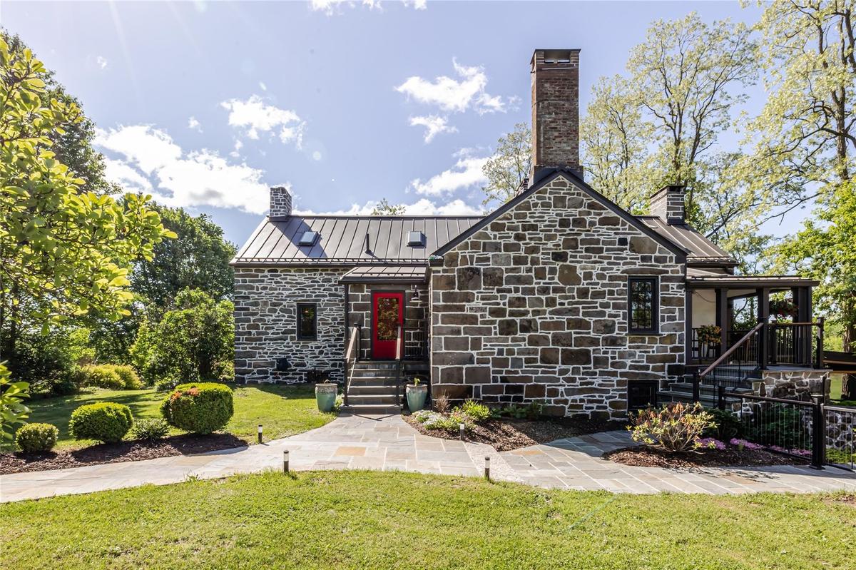 View of front facade featuring a chimney, stone siding, a standing seam roof, and metal roof