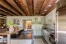 Kitchen featuring stainless steel appliances, wood ceiling with exposed beams, a sink, dark countertops, and a center island