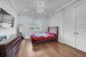 Bedroom featuring wood finished floors, a chandelier, ornamental molding, and a closet