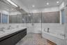 Main Floor Primary Bathroom featuring a garden tub, a stall shower, recessed lighting, double vanity, and tile walls