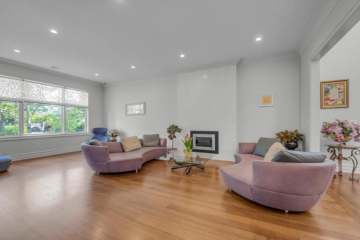 Living room with ornamental molding, light wood finished floors, recessed lighting, and a large gas fireplace