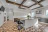 Kitchen with wall chimney range hood, modern cabinets, coffered ceiling, a large island, and healthy amount of natural light