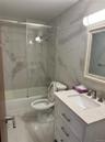 Bathroom featuring combined bath / shower with glass door, marble finish flooring, vanity, and tile walls