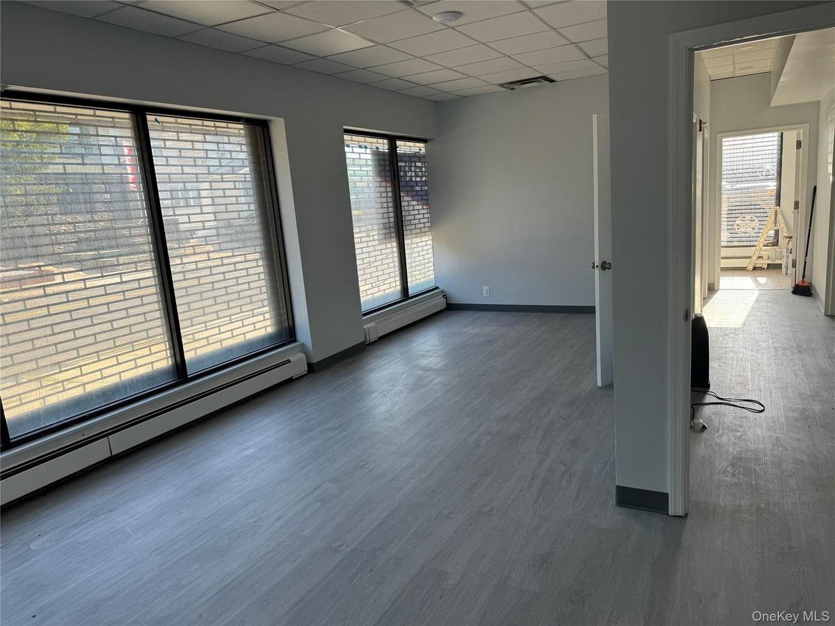 Empty room featuring baseboard heating, a drop ceiling, and wood finished floors