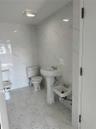 Bathroom with light marble finish floors, tile walls, and stone wall