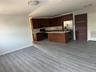 Kitchen featuring dark wood-style floors, appliances with stainless steel finishes, dark brown cabinetry, open floor plan, and a center island