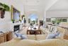 Living room with a high end fireplace, a high ceiling, and wood finished floors