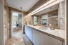 Bathroom with tile walls, a bath, double vanity, and light marble finish floors